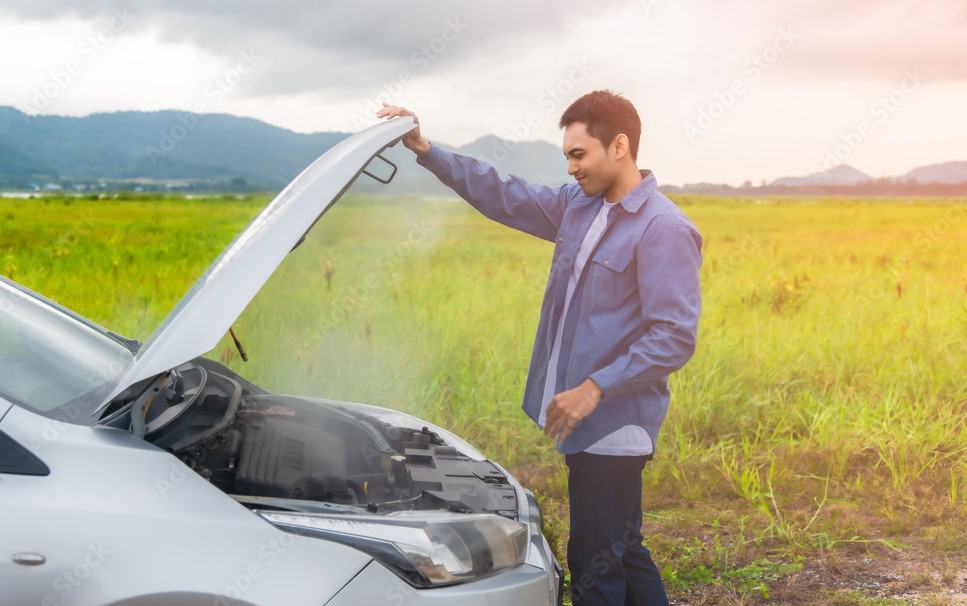 Man opening hood of overheating car